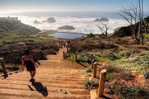 a woman walking up a set of stairs looking at the ocean at Golden Gate Park Sweet Home-2 bedrooms in San Francisco