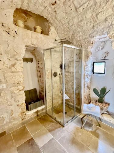 a bathroom with a shower in a stone wall at Relais Grottone in Ostuni