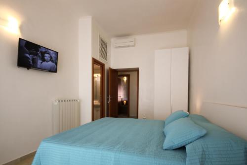 a bedroom with a blue bed and a tv on the wall at San Pietro's Home - Guesthouse in Rome