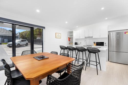 a kitchen and dining room with a wooden table and chairs at Deco Beach Luxury Apartments in Port Lincoln