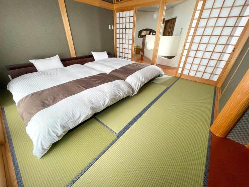 a bedroom with a large bed in a room with windows at Resort villa miko in Oshima