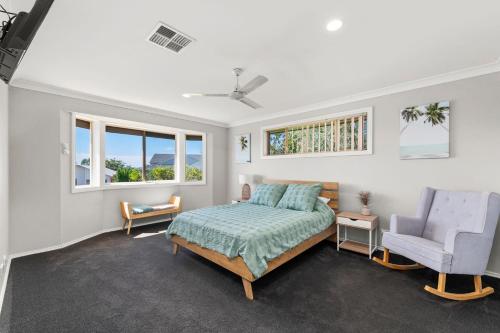 a bedroom with a bed and a chair and windows at Grandview Close 5 Soldiers Point in Soldiers Point