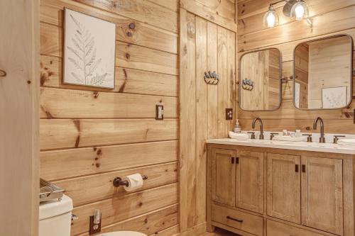 ein Badezimmer mit Holzwänden, einem Waschbecken und einem Spiegel in der Unterkunft Antler Ridge Hideaway in Blue Ridge