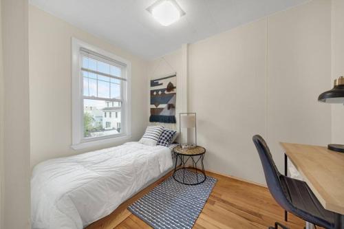 a white bedroom with a bed and a desk at 5BR 2BH Bright & Spacious Apt in Brighton in Boston