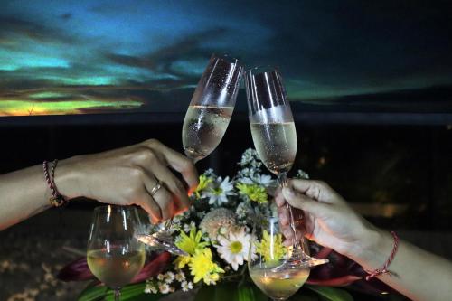 two people holding up wine glasses on a table at MAUA Nusa Penida Bali in Nusa Penida