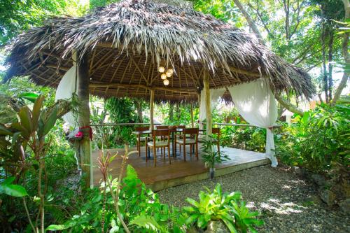 um pátio com uma mesa e cadeiras debaixo de um guarda-sol de palha em Mandala Spa & Resort Villas em Boracay