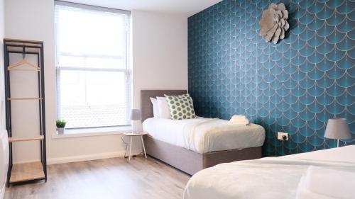 sypialnia z 2 łóżkami i niebieską ścianą w obiekcie Leisure & Contractors - Stylish Town Centre Apartment with Free Parking w mieście Bedford