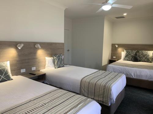 um quarto de hotel com 2 camas e uma ventoinha de tecto em Hamilton Henry Parkes Motor Inn em Parkes