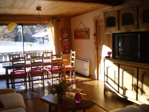 ein Wohnzimmer mit einem Tisch, Stühlen und einem TV in der Unterkunft Appartement La Montagne in Les Gets