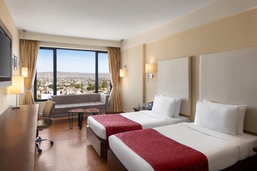 a hotel room with two beds and a large window at Ramada by Wyndham Jaipur North in Jaipur