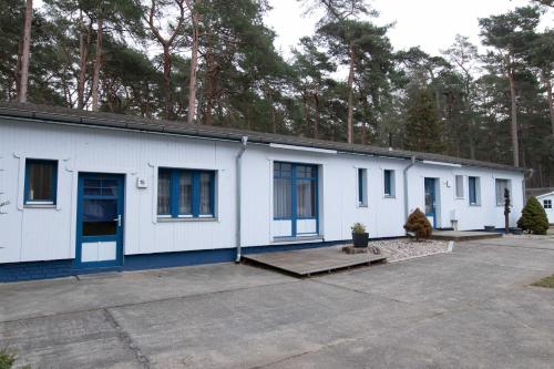 ein weißes Gebäude mit blauen Türen und Fenstern in der Unterkunft Ferienanlage Zum Knirk in Lubmin