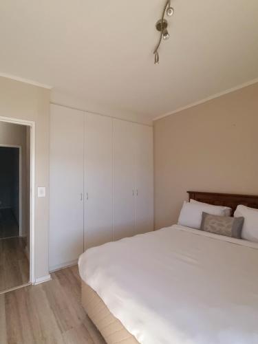 a bedroom with a large white bed and white cabinets at Island Club by Smart City Stays in Cape Town