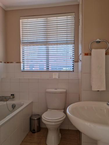 a bathroom with a toilet and a tub and a sink at Island Club by Smart City Stays in Cape Town