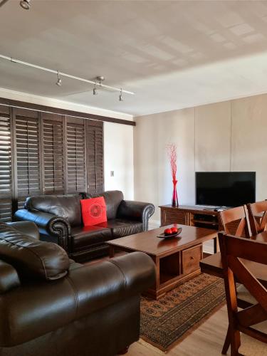 a living room with a leather couch and a table at Island Club by Smart City Stays in Cape Town