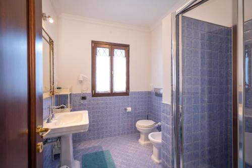 a blue tiled bathroom with a toilet and a sink at La casa di Chiara in Diano dʼAlba