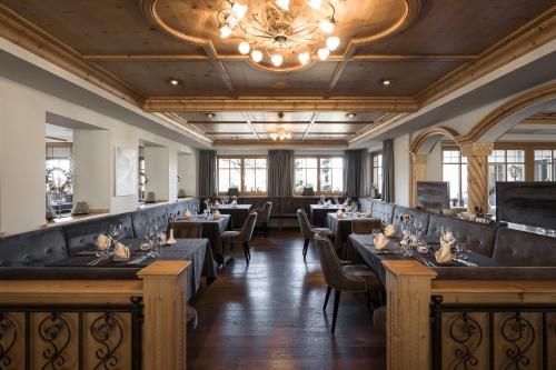 a dining room with tables and chairs and a chandelier at Hotel Viertler in Avelengo