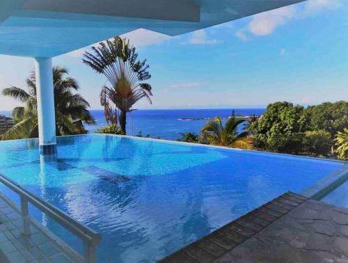 a large swimming pool with a view of the ocean at Grand Large - cosy studio in Papeete