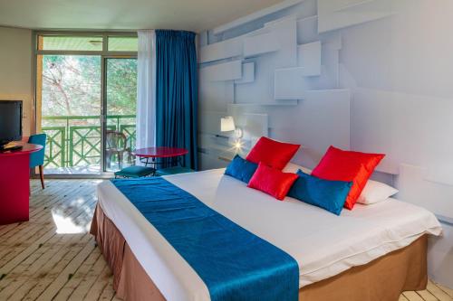 a bedroom with a large bed with red and blue pillows at Garrigae Domaine de l'Esterel in Saint-Raphaël