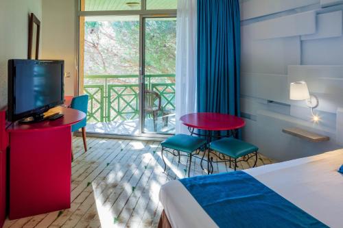 a hotel room with a bed and a tv and a window at Garrigae Domaine de l'Esterel - piscine & SPA Cinq Mondes in Saint-Raphaël