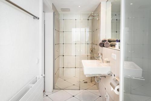 a white bathroom with a sink and a shower at Villa am First in Oberstdorf