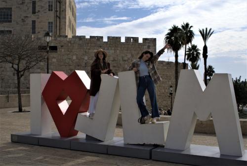 two women are standing on top of a large sign at The Post Hostel Jerusalem in Jerusalem