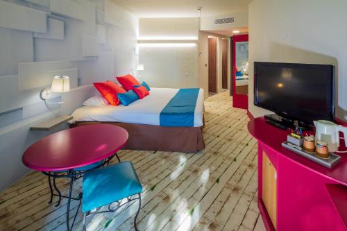 a hotel room with a bed and a flat screen tv at Garrigae Domaine de l'Esterel - piscine & SPA Cinq Mondes in Saint-Raphaël