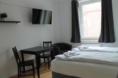 a bedroom with a bed and a table and a window at Boardinghouse Georgsheil in Südbrookmerland