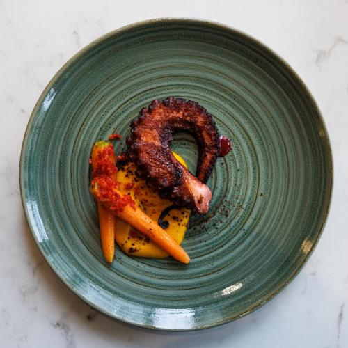a green plate with meat and carrots on a table at Grand Hotel d'Orange, BW Signature Collection in Orange