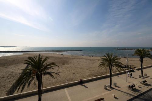 une vue sur une plage avec des palmiers et l'océan dans l'établissement La Croix du Sud superbe appartement en duplex 2 chambres vue mer, au Grau-du-Roi