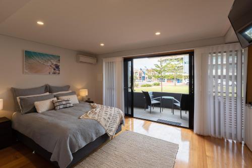a bedroom with a bed and a balcony with a table at Promenade Unit 4 in Geraldton