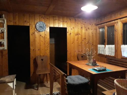 ein Esszimmer mit einem Tisch und einer Uhr an der Wand in der Unterkunft Chata - Na samotě u lesa in Levín
