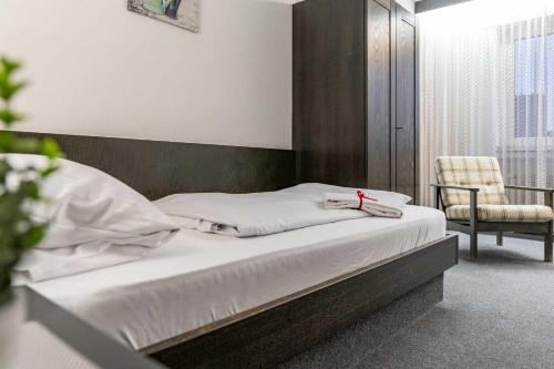 Cette chambre comprend un lit avec des draps blancs et une chaise. dans l'établissement Hotel Wildpferd Dülmen, à Dülmen
