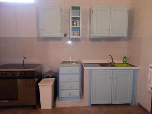 una cocina con armarios blancos y fregadero en La Casa di Muro en Oriolo Romano