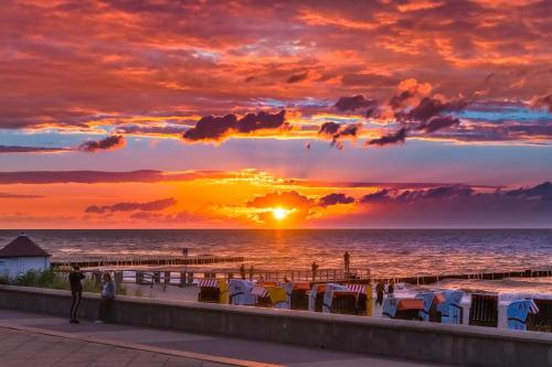 a sunset on a beach with chairs and the ocean at Ferienwohnung Tor zum Meer - Neubau mit Sauna, Fahrstuhl und Tiefgarage in Kühlungsborn