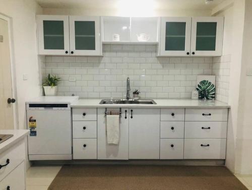 a kitchen with white cabinets and a sink at Suva City Accommodation in Suva