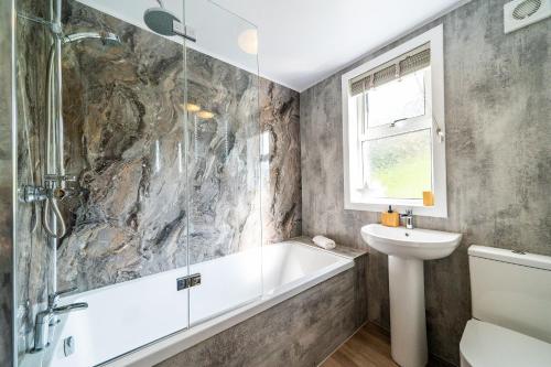 a bathroom with a bath tub and a sink at Lagnaha Cottage in Kentallen