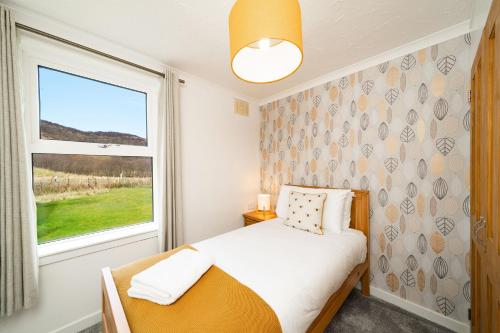 una piccola camera da letto con un letto e una finestra di Lagnaha Cottage a Kentallen