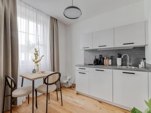 a kitchen with white cabinets and a table and chairs at limehome Villach Gerbergasse in Villach