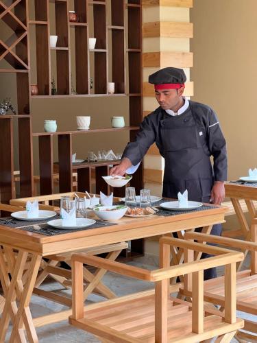 un chef parado frente a una mesa en The Country House, en Lachung