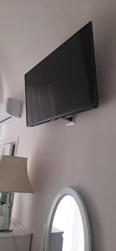 Elle comprend une télévision à écran plat suspendue sur un mur à côté d'un miroir. dans l'établissement B&B La Maddalena, à Sammichele di Bari