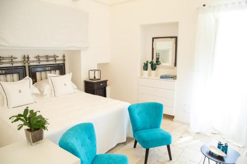 a bedroom with a white bed and blue chairs at Dimora Graziana 1909 in Locorotondo