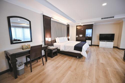 een hotelkamer met een bed, een bureau en een televisie bij PRIME CITY HOTEL KLUANG in Kluang