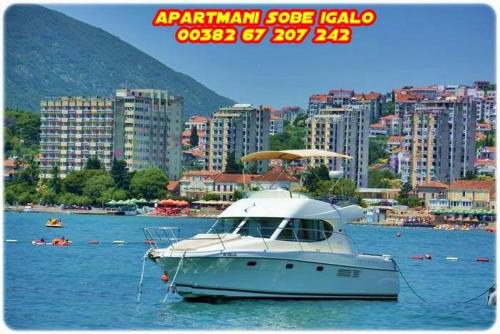 a white boat in the water in a city at Apartments Igalo Montenegro in Igalo