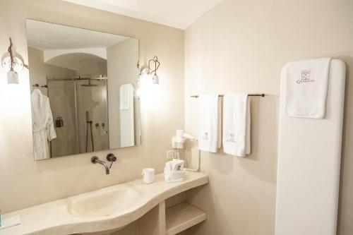 a white bathroom with a sink and a mirror at Dimora Graziana 1909 in Locorotondo