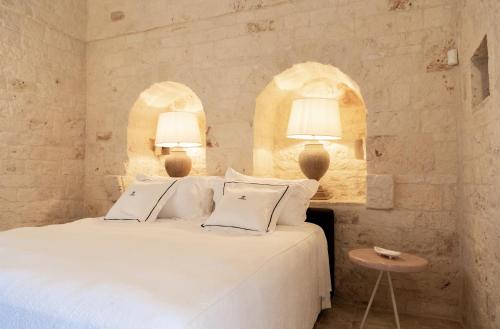a bedroom with a white bed with two lamps at Dimora Graziana 1909 in Locorotondo