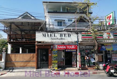 a building with a mittel fed sign on a street at MIEL BED Hostel & Gallery in Chiang Mai