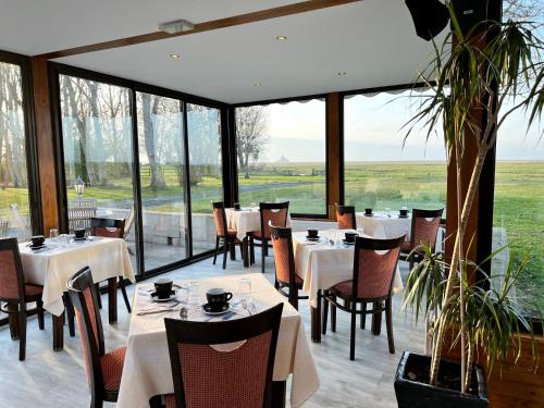 un restaurant avec des tables, des chaises et des fenêtres dans l'établissement Manoir de la Roche Torin, The Originals Relais, à Courtils