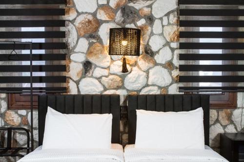 a bedroom with two beds and a stone wall at The Stone Forest in Kalabaka
