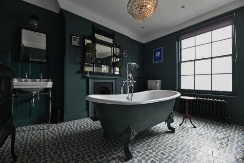 KentにあるOpulent Georgian townhouse overlooking Spencer Squareの緑豊かなバスルーム(バスタブ、シンク付)
