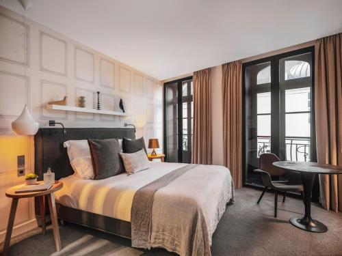 a bedroom with a bed and a table and a desk at Balthazar H&ocirc;tel & Spa Rennes - MGallery Hotel Collection in Rennes